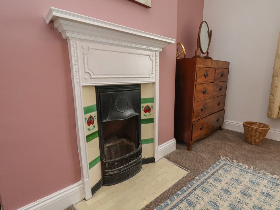 A bedroom with a fireplace and a chest of drawers at The Manse in Whitby