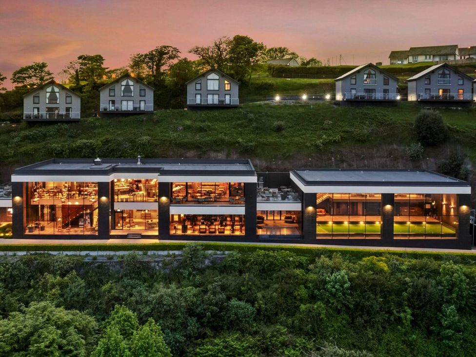 A modern building with large windows and outdoor seating at Ferry Hills in Laugharne