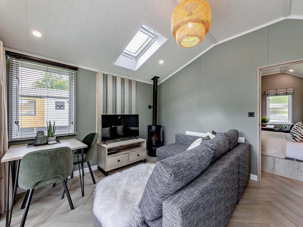 A living room with a sofa dining table and television at Prion Spa in Llandyrnog