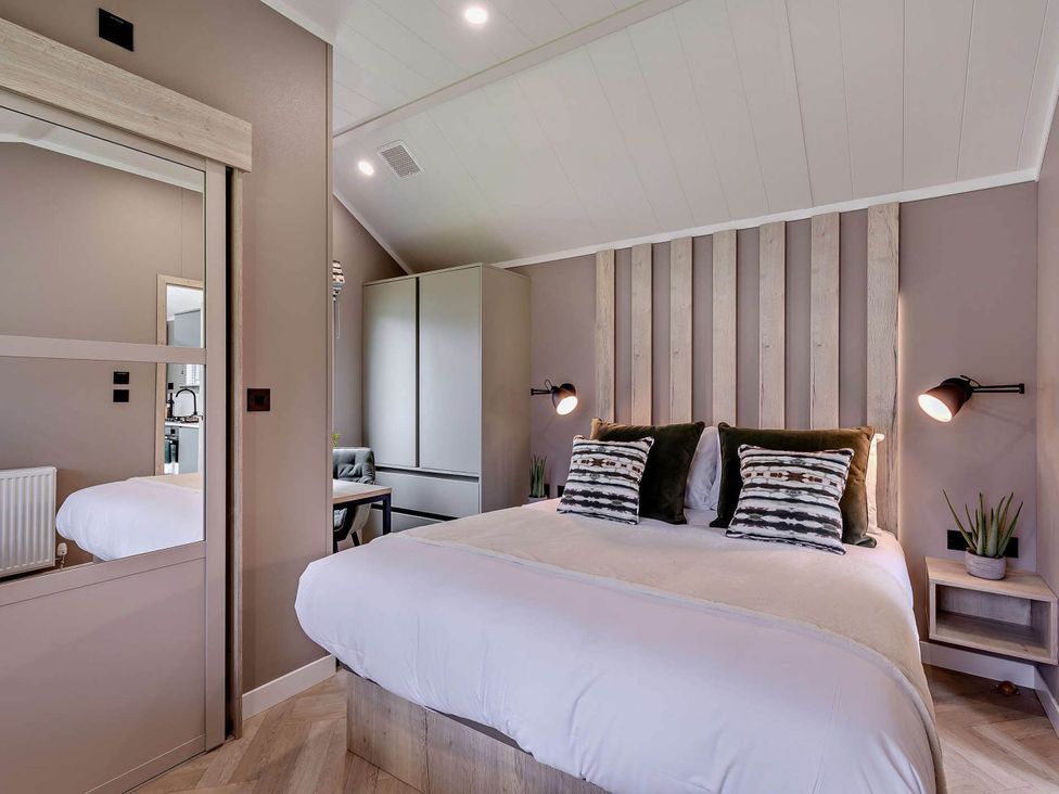 A bedroom with a bed and wardrobe at Prion Spa in Llandyrnog