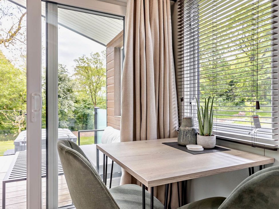 A dining area with a table and chairs near a window at Prion Spa Llandyrnog