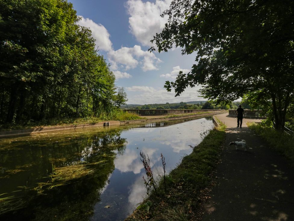 A pathway alongside water with trees and a person walking a dog at Aqueduct Residence in Lancaster