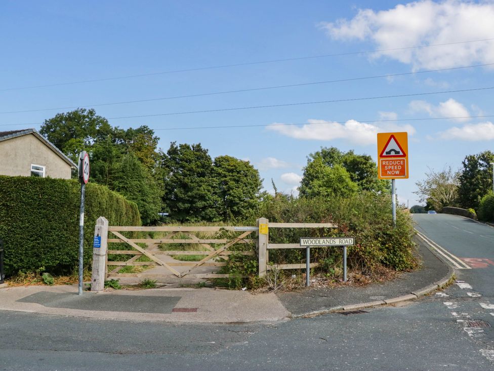 An outdoor view of Woodlands Road with signs and a gate at Aqueduct Residence in Lancaster