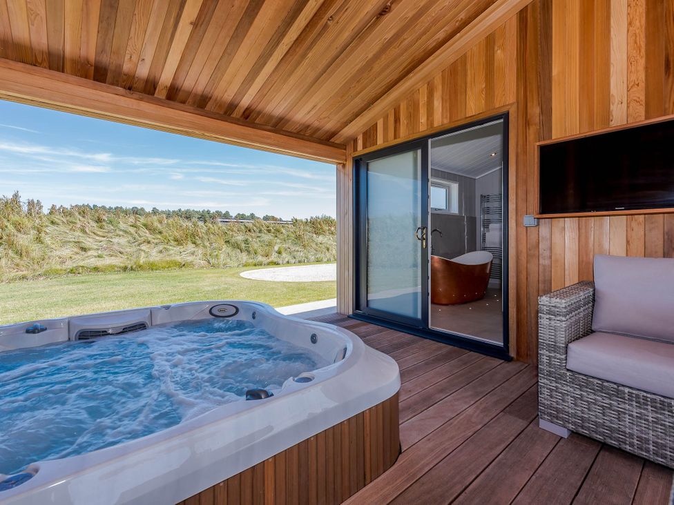 An outdoor area with a hot tub and glass door at Darwin Retreat in Wigton
