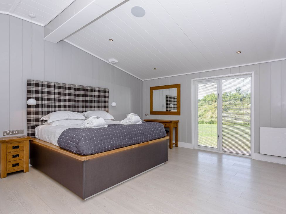 A bedroom with a bed and a mirror at Darwin Retreat in Wigton
