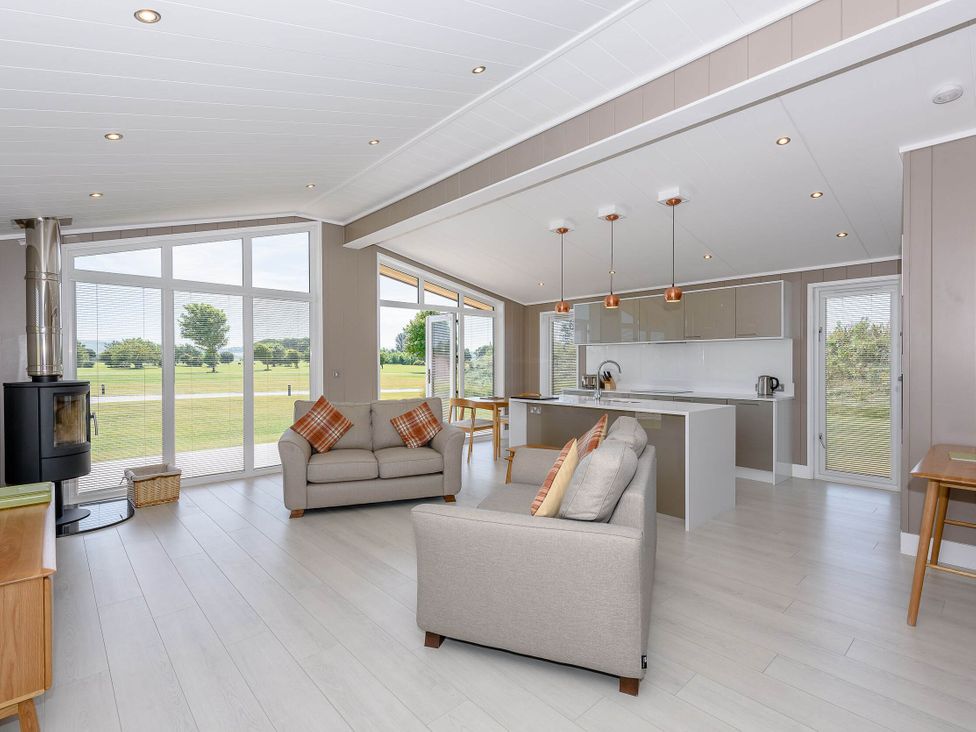 A living room with a sofa and kitchen area at Darwin Retreat in Wigton