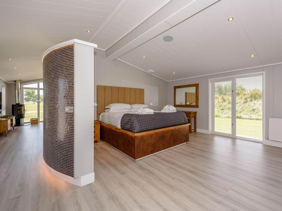 A bedroom with a bed and a mirror at Darwin Retreat in Wigton