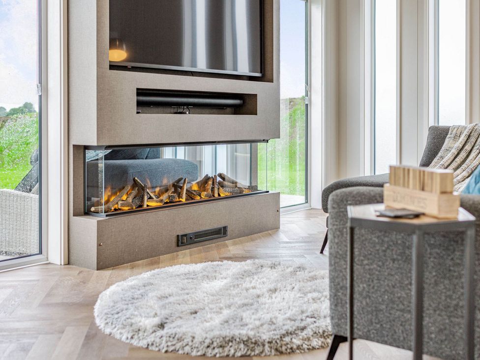 A living room with a fireplace and television at The Sheraton Retreat in Wigton