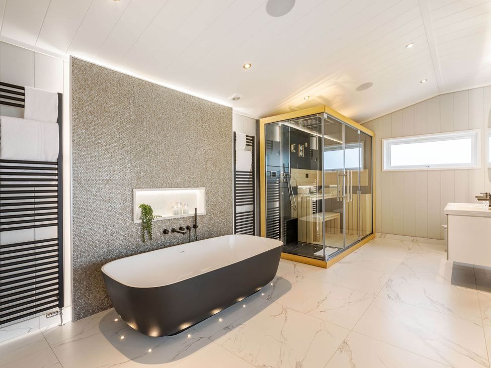 A bathroom with a bathtub and shower enclosure at The Sheraton Retreat in Wigton