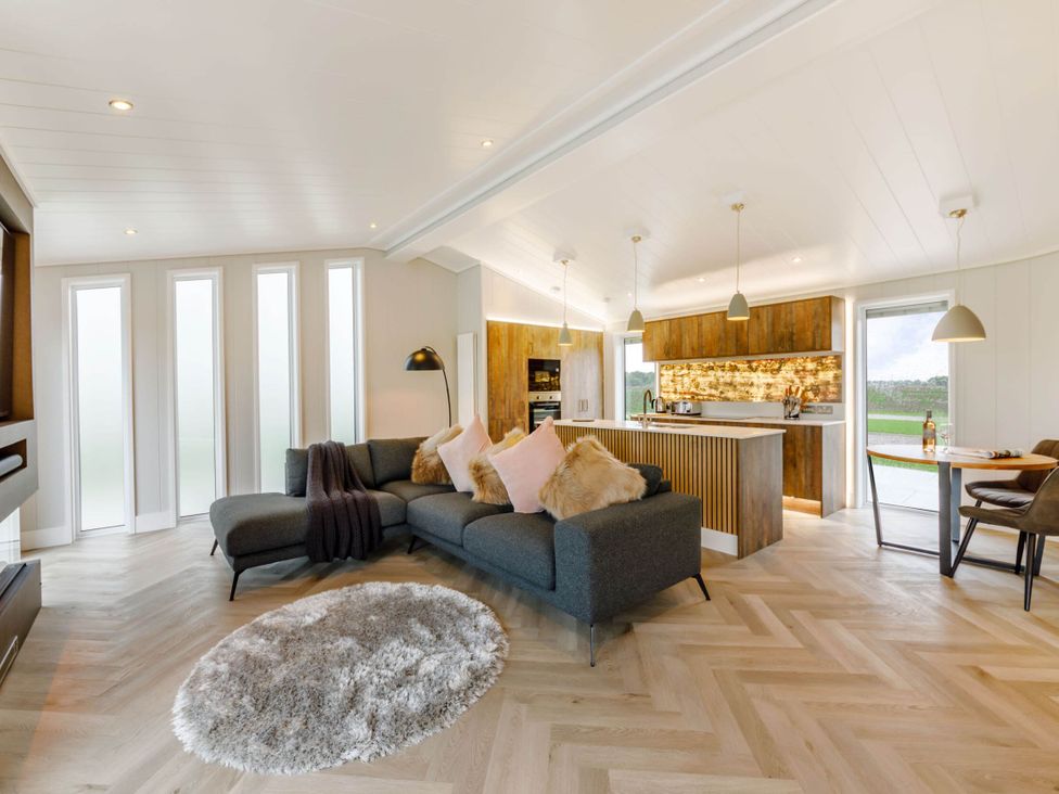 A living room with a sofa and kitchen area at The Sheraton Retreat in Wigton