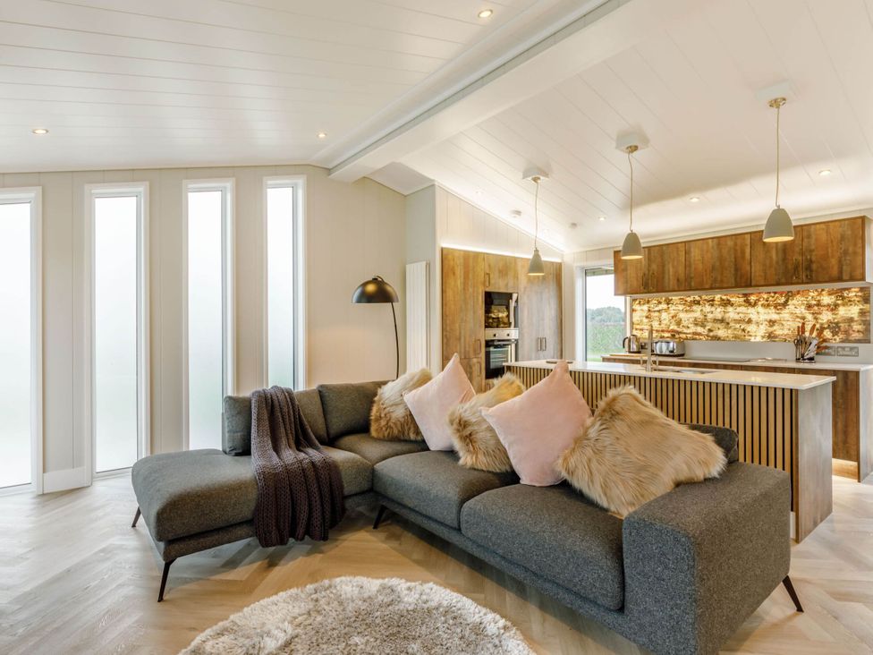 A living room with a sofa and kitchen area at The Sheraton Retreat in Wigton