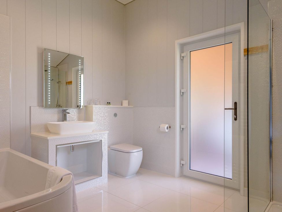 A bathroom with a bathtub, sink, mirror, and shower at Wordsworth in Wigton