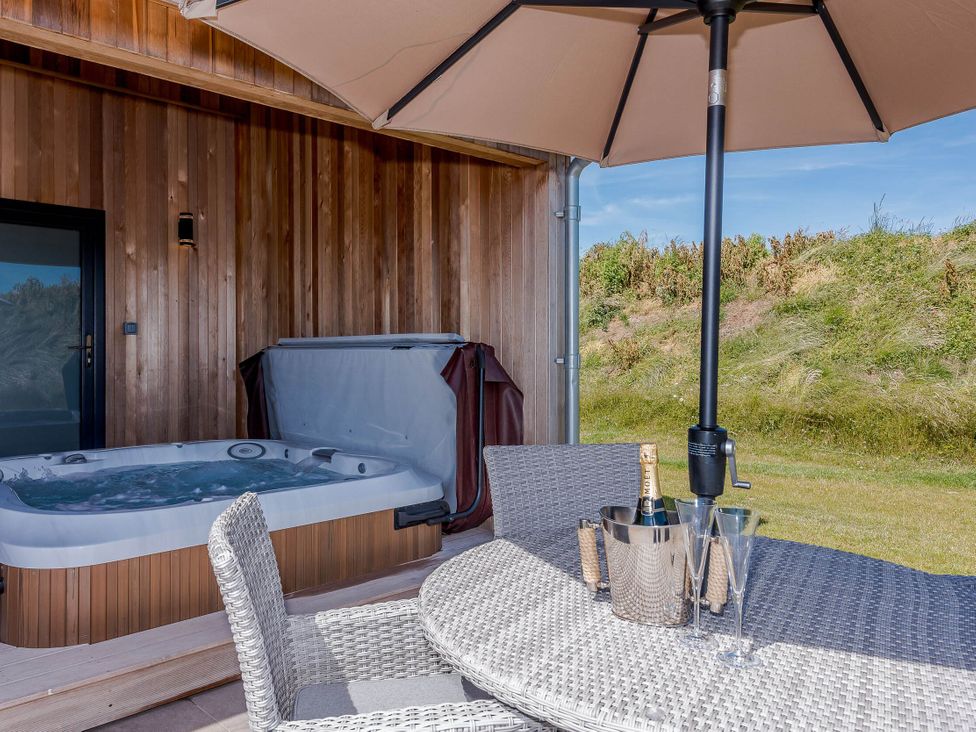 An outdoor area with a hot tub and table with champagne at Wordsworth in Wigton