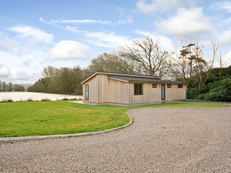 A wooden house with a gravel driveway and grassy area at Lawson in Wigton