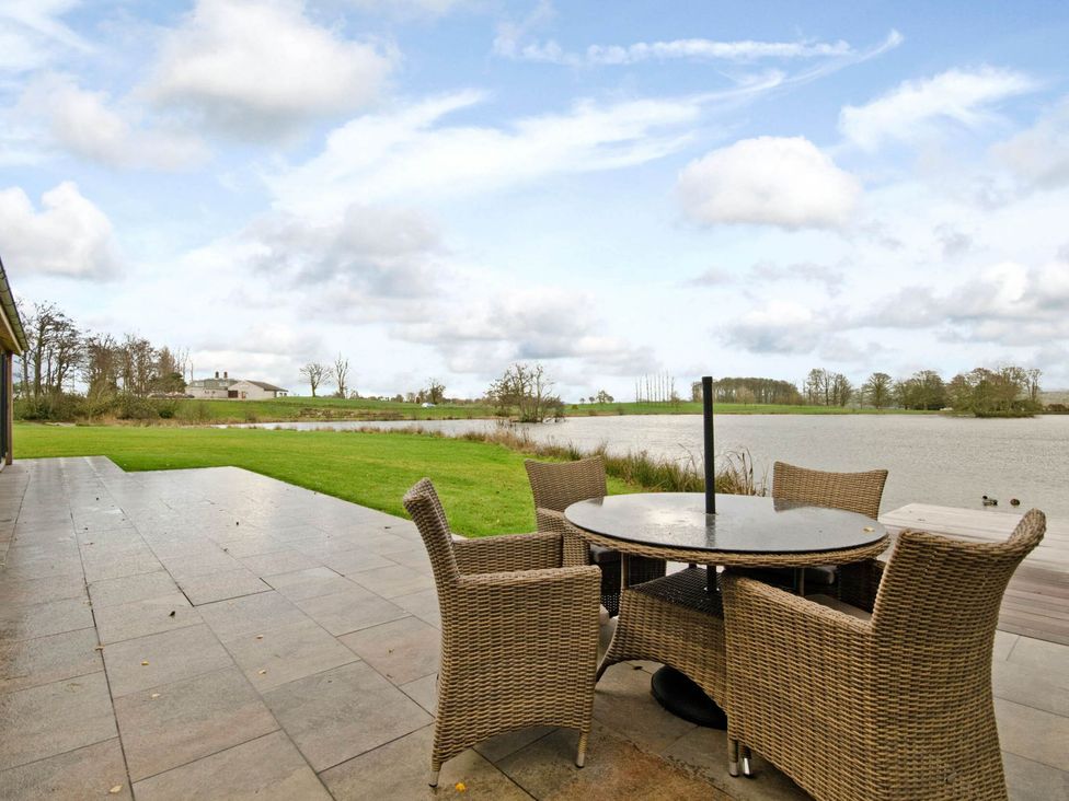 An outdoor area with a table and chairs by a lake at Lawson in Wigton