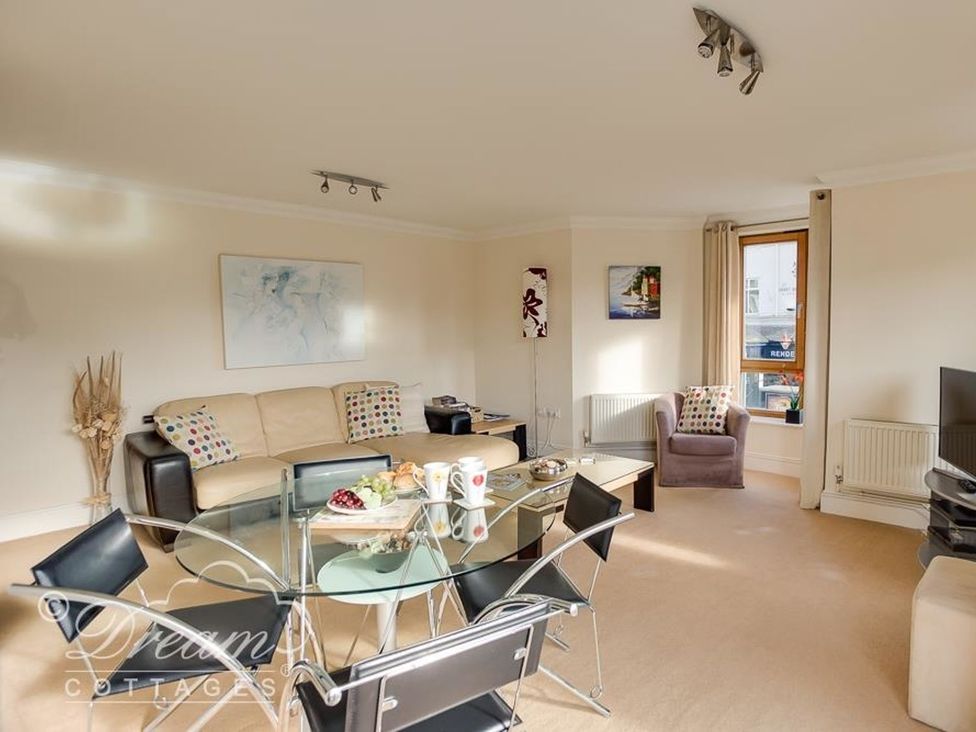 A living room with a sofa, dining table and television at Harbourside Apartment in Weymouth