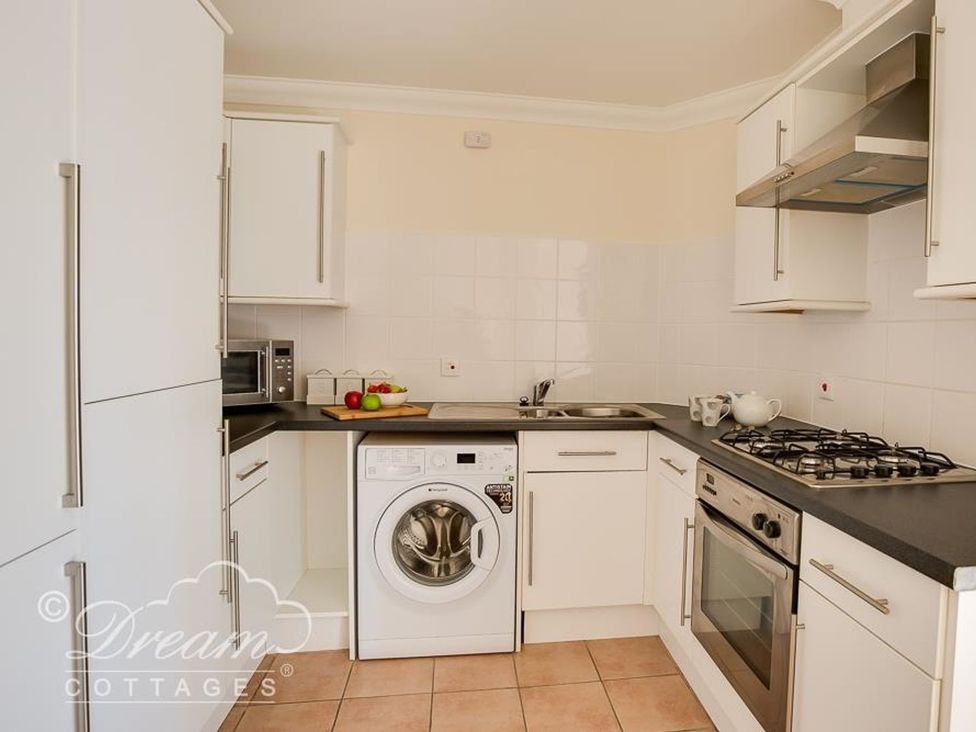 A kitchen with a washing machine, stove and microwave at Harbourside Apartment in Weymouth