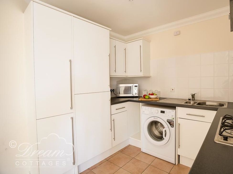 A kitchen with a washing machine and microwave at Harbourside Apartment in Weymouth