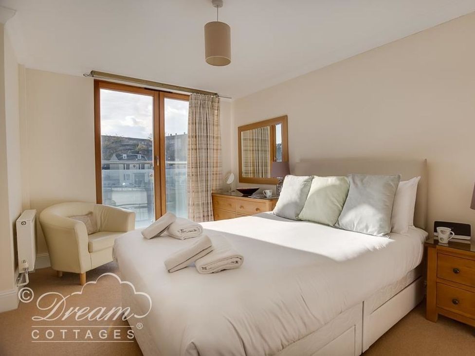 A bedroom with a bed and chair at Harbourside Apartment in Weymouth