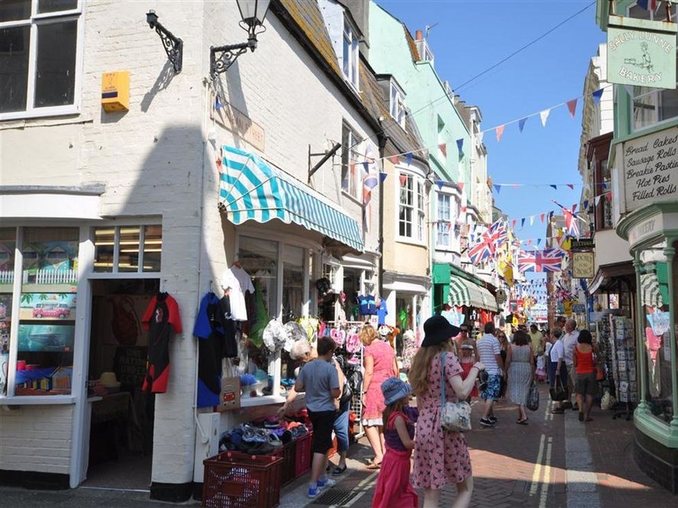 A busy shopping street with shops and pedestrians at Harbourside Apartment in Weymouth