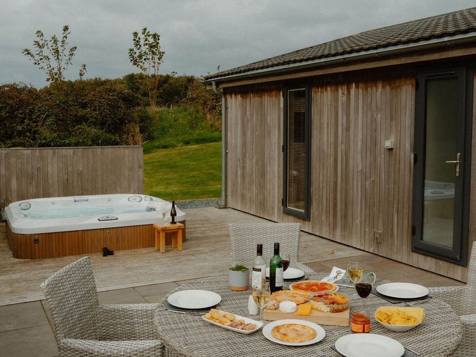 An outdoor patio with a hot tub and table set with food and drinks at Wellington in Wigton