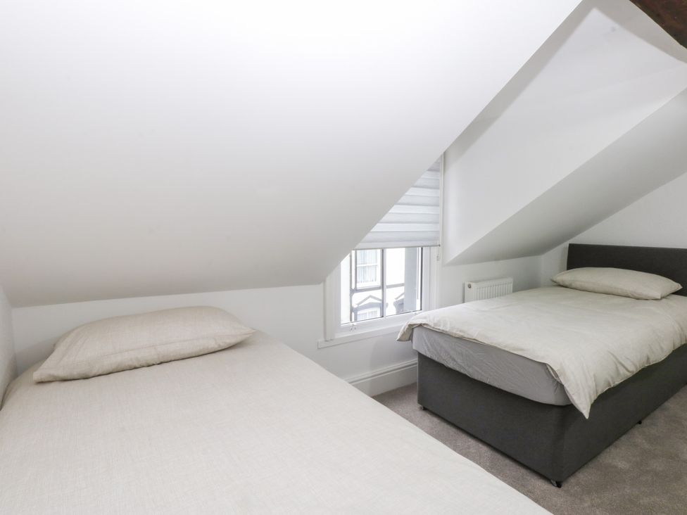 A bedroom with two beds and a window at 6 Berry Street in Conwy