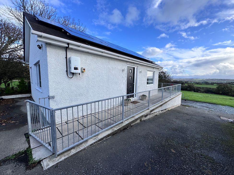 A house with solar panels and a railing at Ty Nain in Bodorgan