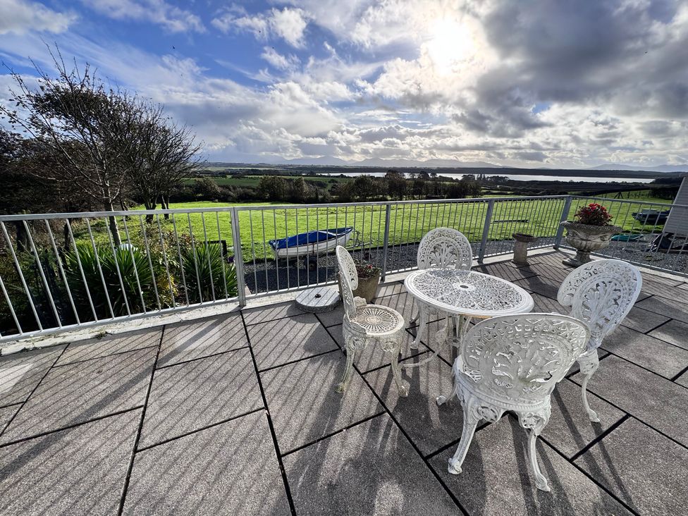 An outdoor seating area with a table and chairs overlooking a green landscape at Ty Nain in Bodorgan