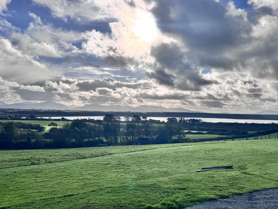 A scenic view of a lake and mountains under a cloudy sky at Ty Nain in Bodorgan
