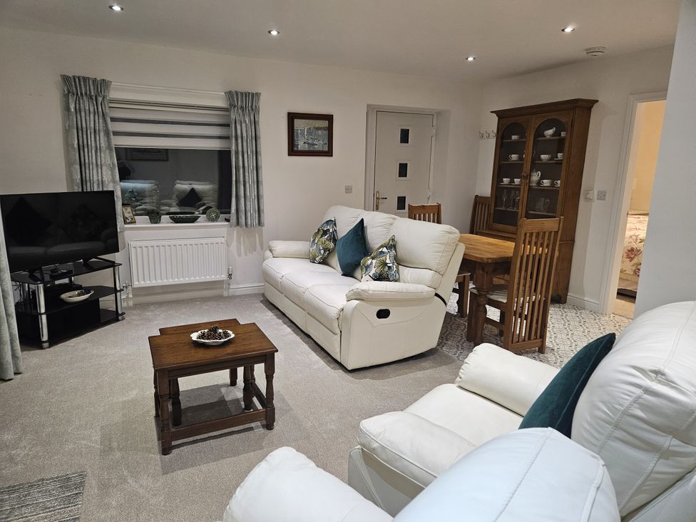 A living room with a sofa, television, and dining table at Ty Nain in Bethel