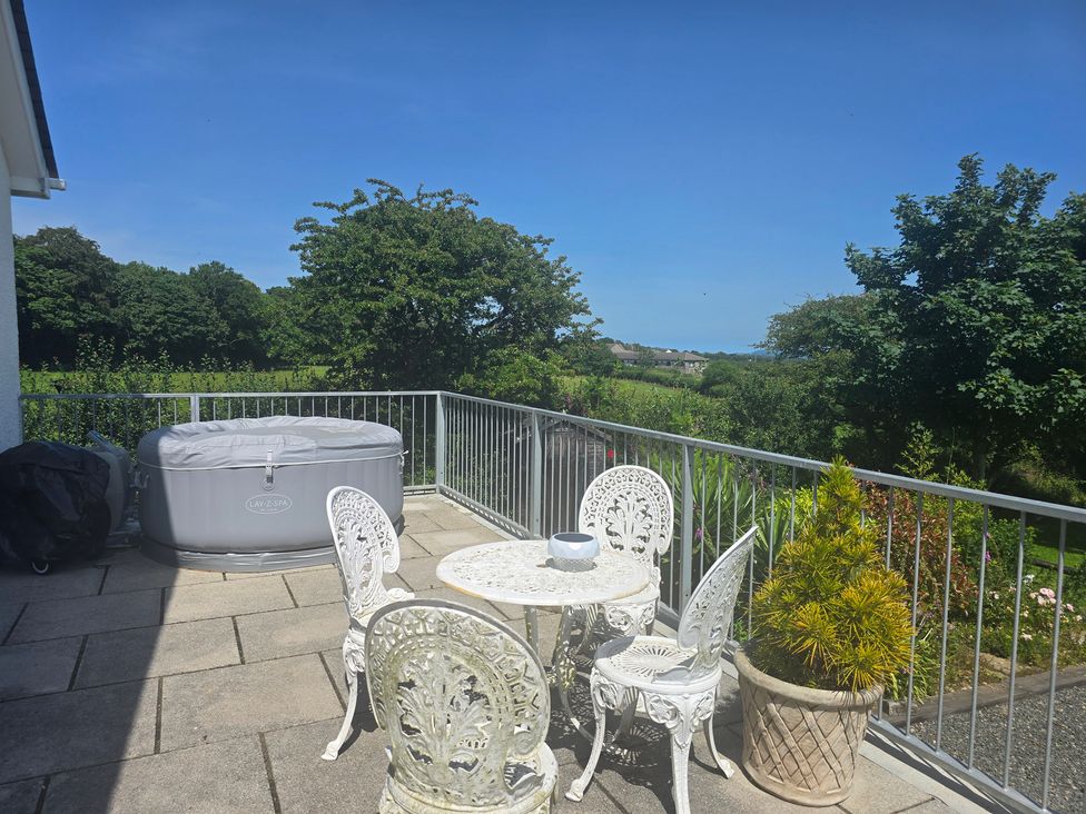 An outdoor patio with a hot tub and a table with chairs at Ty Nain in Bethel