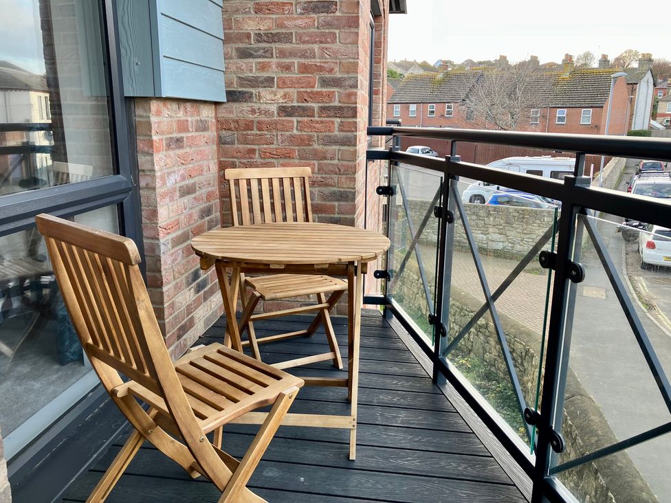 A balcony with a wooden table and chairs at 12 Brewhouse Place, Weymouth