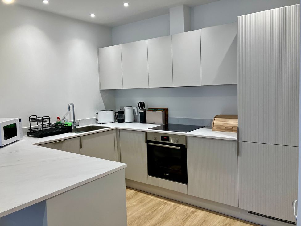 A kitchen with a sink, microwave, oven, and cabinets at 12 Brewhouse Place in Weymouth