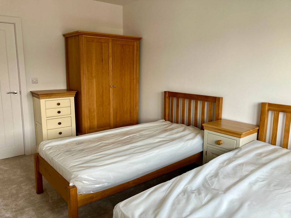 A bedroom with two beds and a wardrobe at 12 Brewhouse Place in Weymouth