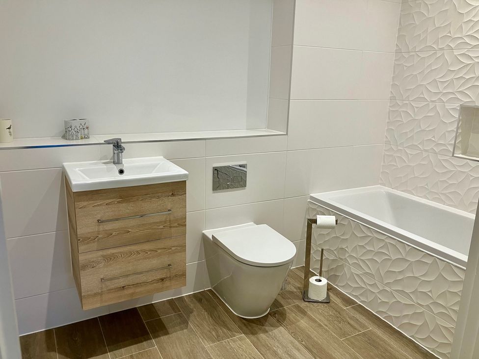 A bathroom with a sink, vanity, toilet, and bathtub at 12 Brewhouse Place in Weymouth