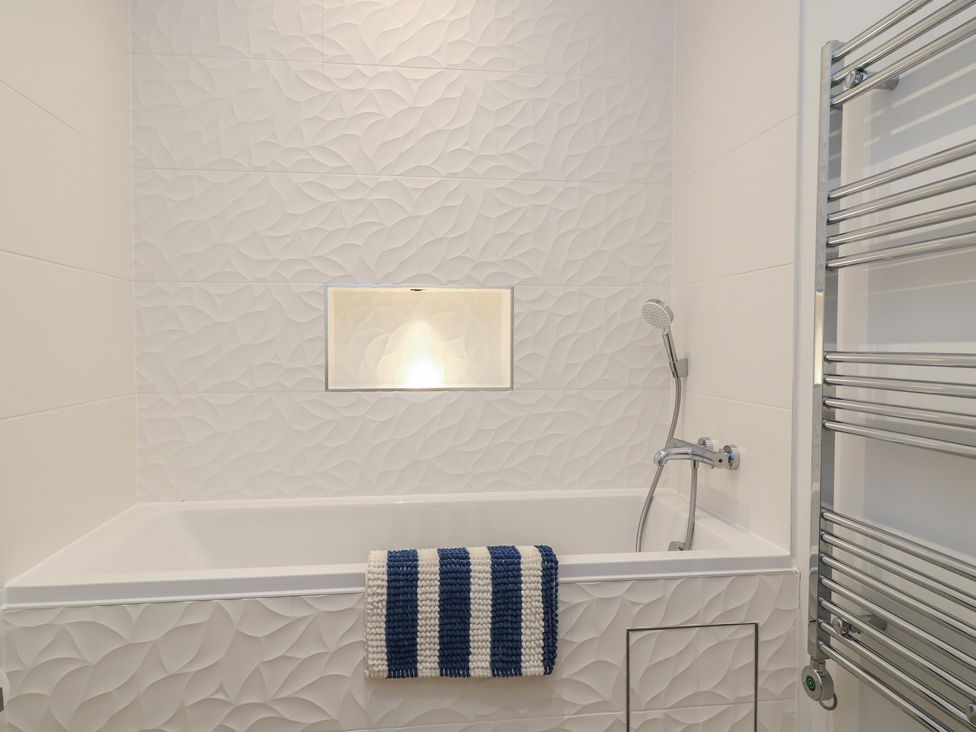 A bathroom with a bathtub and showerhead at Brewery View in Weymouth