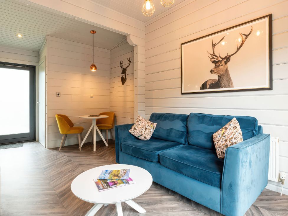A living room with a blue sofa and a dining area at Askrigg (Pet) Aysgarth