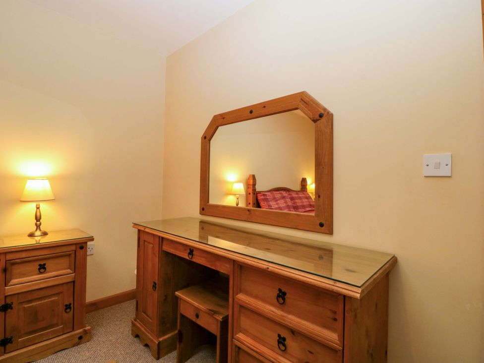 A bedroom with a dressing table and lamp at Dovecote Cottage near Gloucester