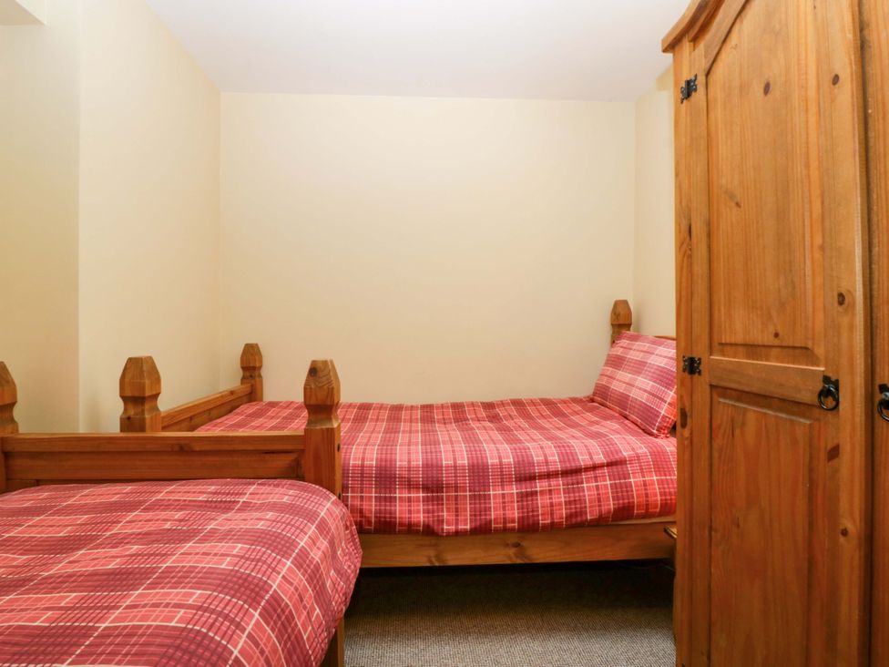 A bedroom with two beds and a wardrobe at Dovecote Cottage Corse near Gloucester