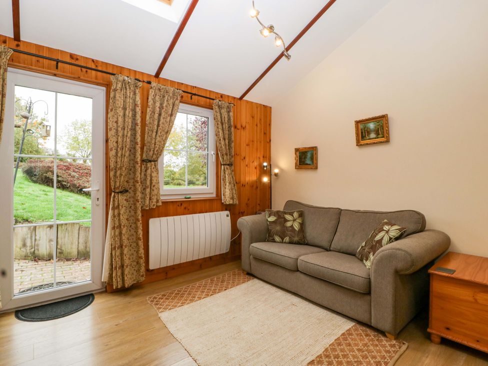 A living room with a sofa and window at The Log Cabin in Corse near Gloucester