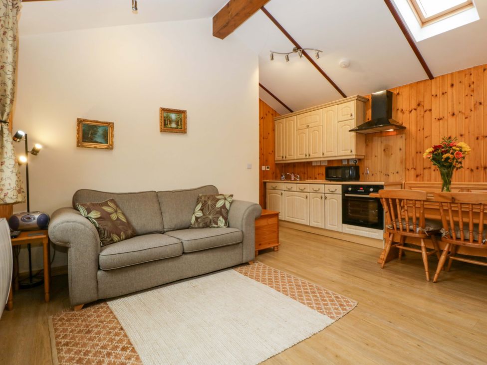A living room with a sofa and kitchen area at The Log Cabin Corse near Gloucester