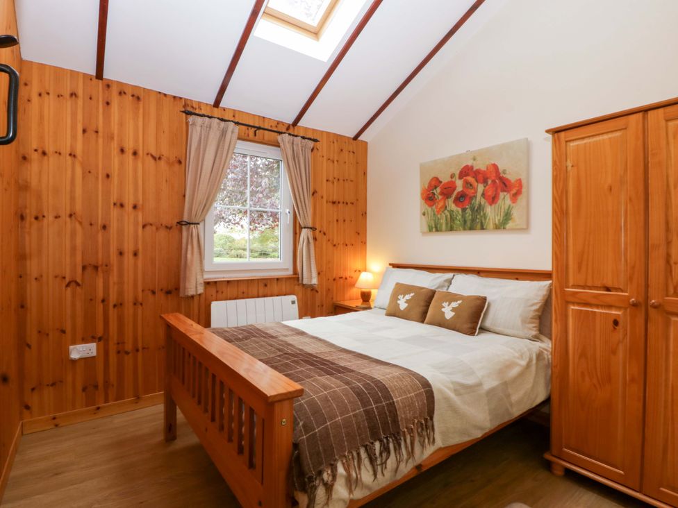 A bedroom with a bed and wardrobe at The Log Cabin in Corse near Gloucester
