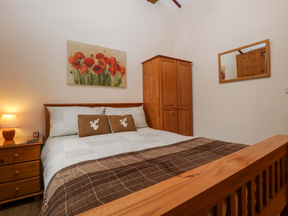 A bedroom with a bed and wardrobe at The Log Cabin in Corse near Gloucester