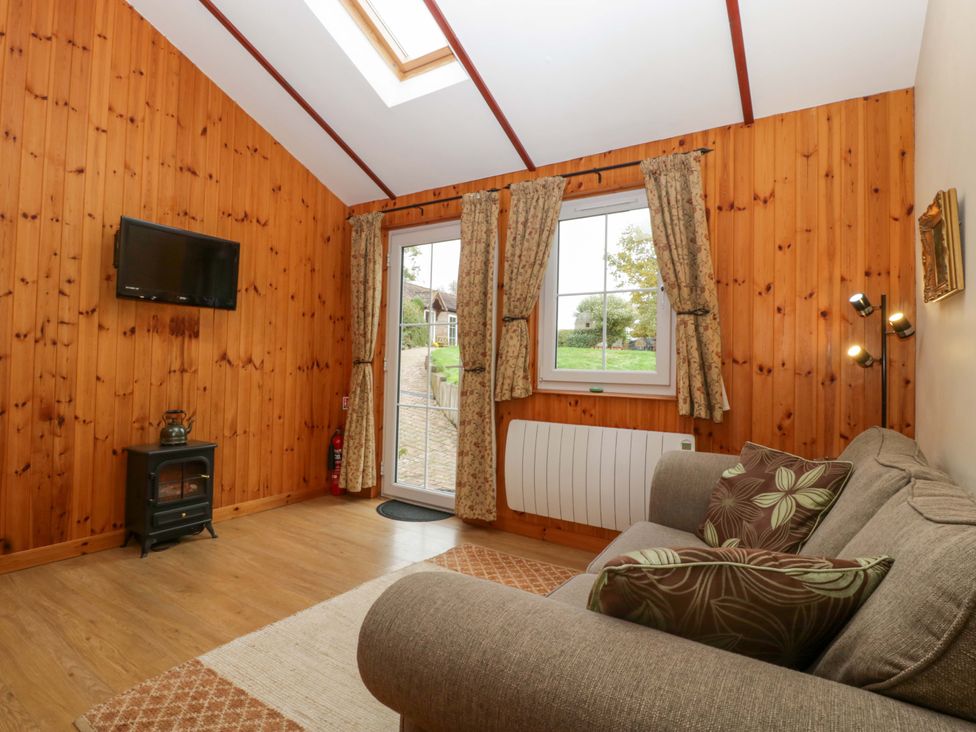 A snug room with a sofa and television at The Log Cabin in Corse near Gloucester