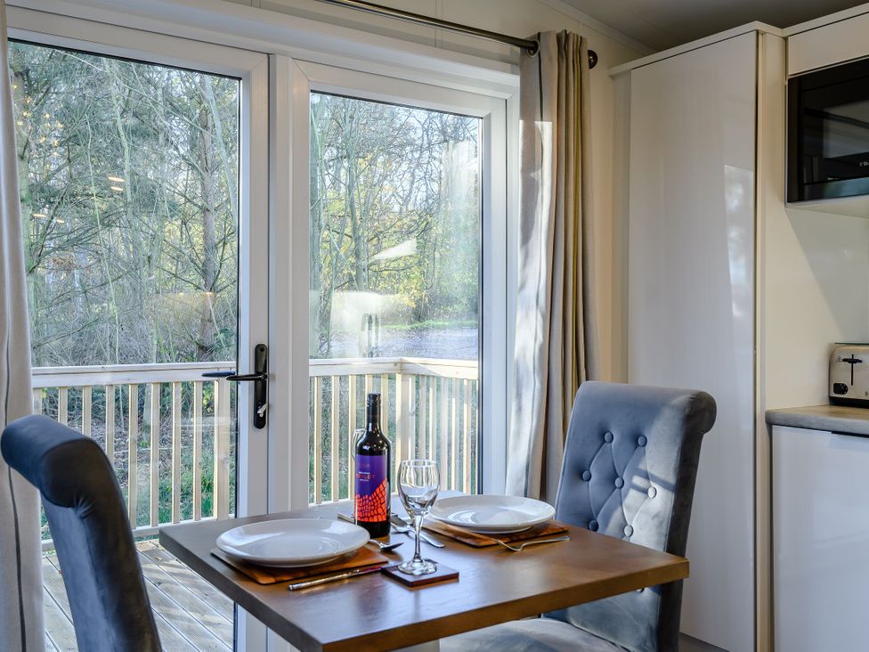 A dining area with a table and chairs overlooking a deck at Somersby Spa in Louth