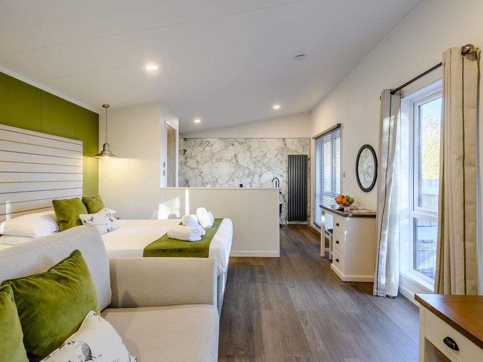 A bedroom with a bed, sofa, and kitchenette at Somersby Spa in Louth
