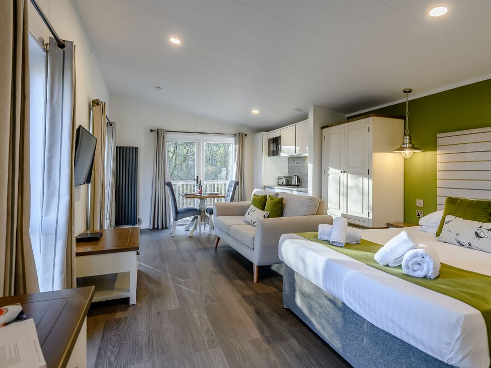 A living room with a sofa and kitchenette at Somersby Spa in Louth