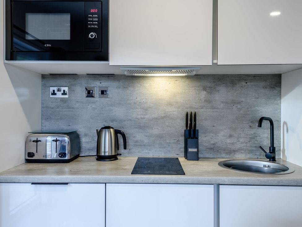 A kitchen with a microwave toaster kettle and sink at Somersby Spa in Louth