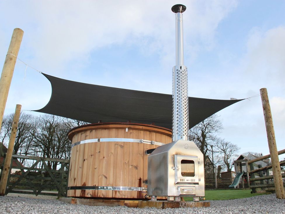 An outdoor hot tub with a chimney and canopy at Higher Forda in Holsworthy