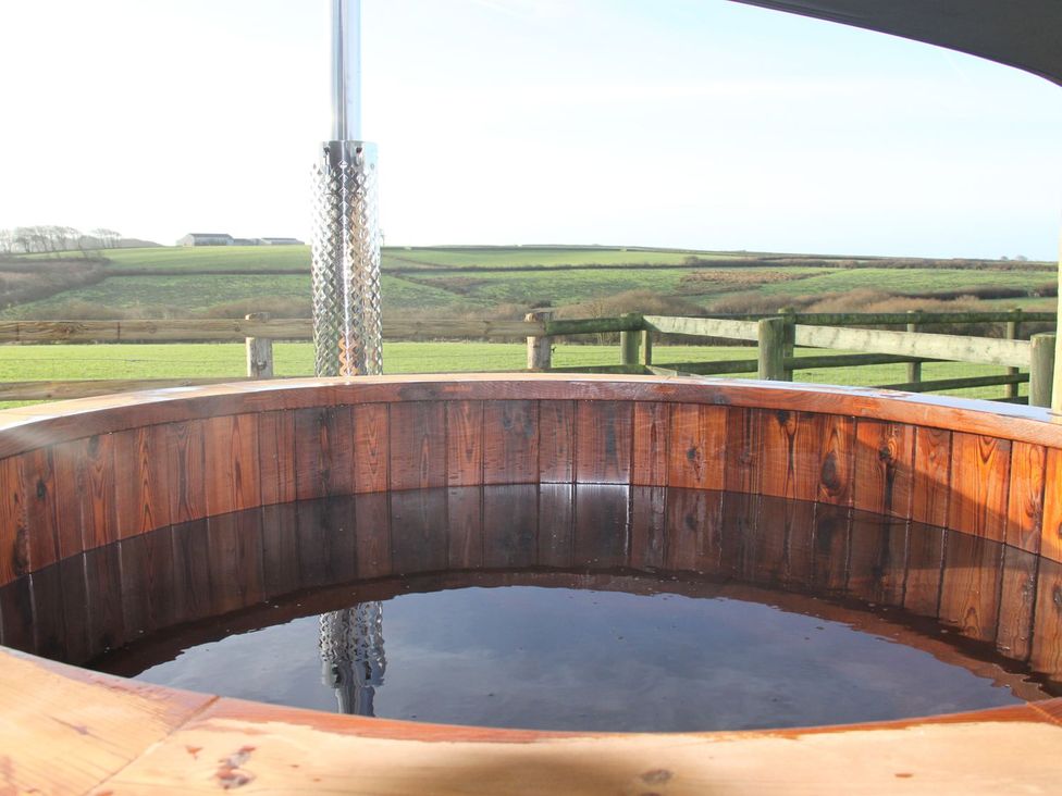 A hot tub with a wooden surround in an outdoor area at Higher Forda in Holsworthy
